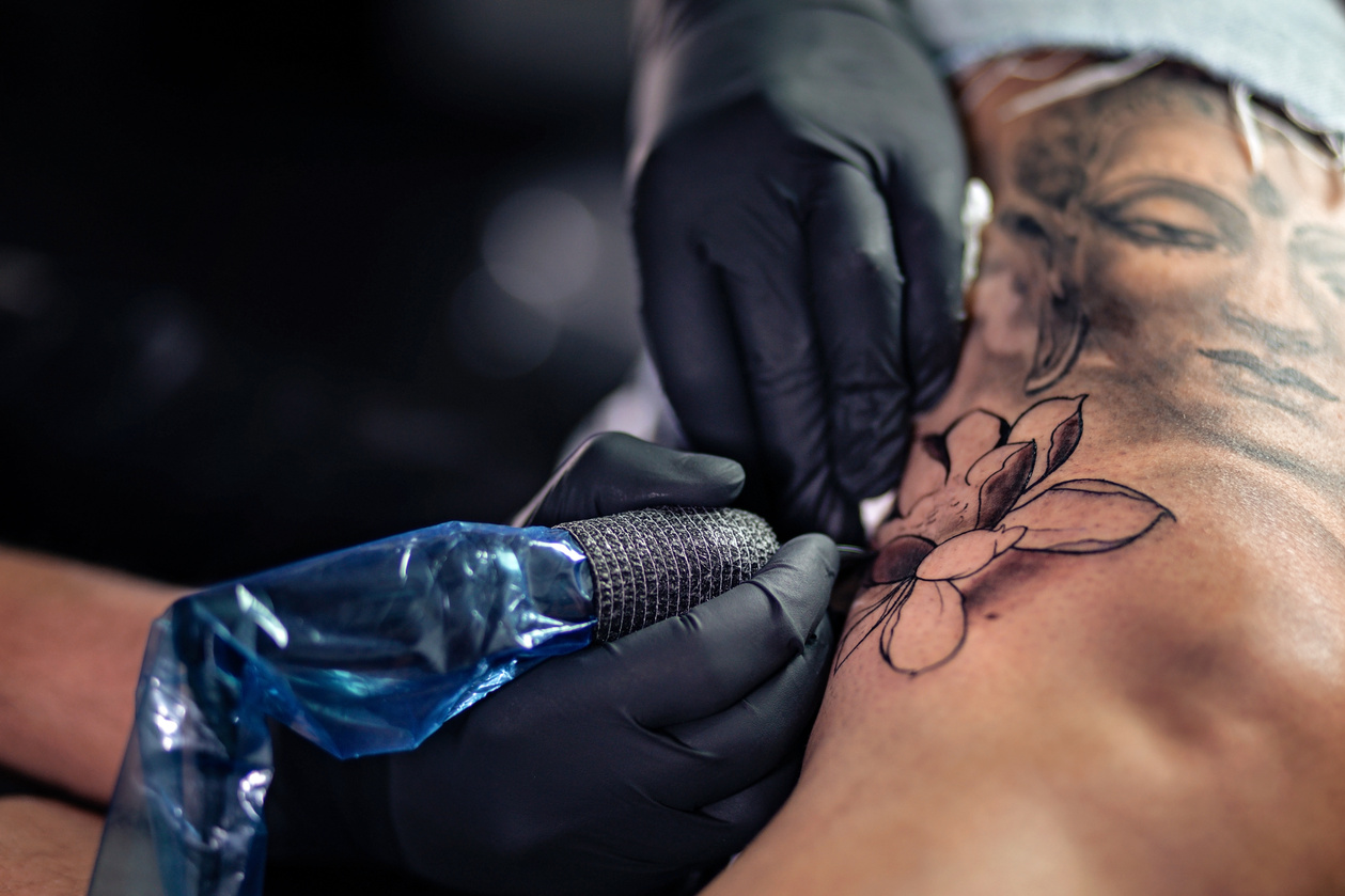 Tattoo artist making tattoo on woman leg